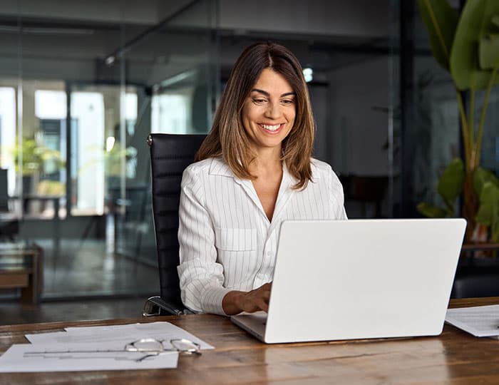 Mitarbeiterin arbeitet lächelnd am Laptop